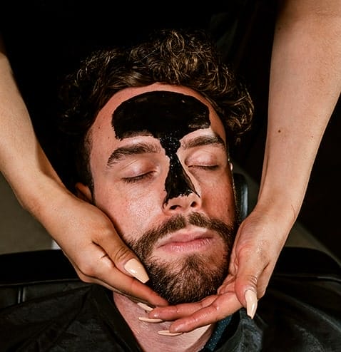 man with skin mask receiving a facial massage