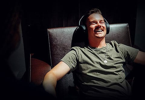 man with headphones on relaxes in leather chair